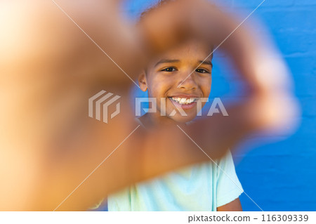 Biracial boy smiles through a heart shape made with hands 116309339