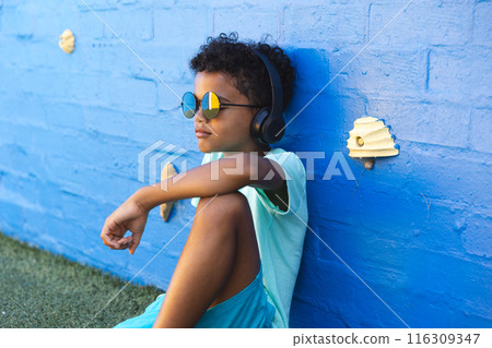 Biracial boy wearing sunglasses enjoys music outdoors 116309347