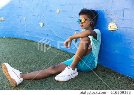 Biracial boy enjoys music outdoors, with copy space 116309353