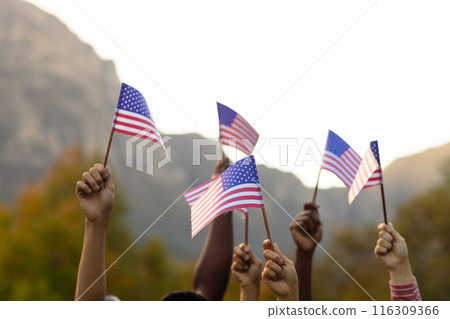 Diverse friends raising hands with flags of usa in garden Diverse friends raising hands with flags of usa in garden 116309366