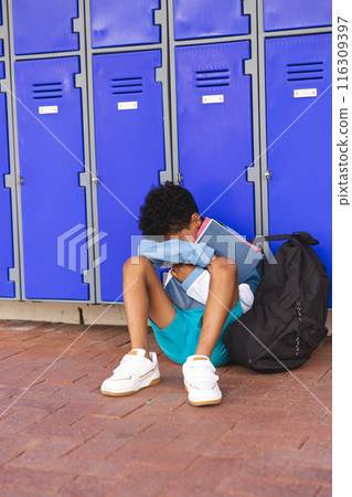 Biracial boy sitting alone at school, looking upset Biracial boy sitting alone at school, looking upset 116309397
