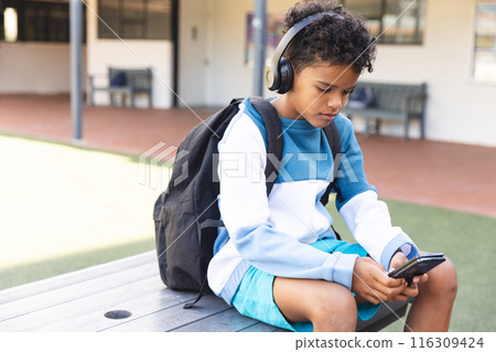 Biracial boy enjoys music on school grounds 116309424