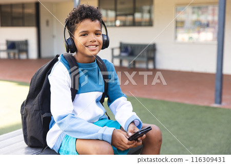 Biracial boy enjoys music at school, with copy space 116309431