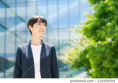 A woman in a suit standing in front of an office building A woman in a suit standing in front of an office building 116309504