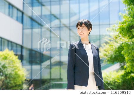 一位穿著西裝的女士站在辦公大樓前 116309513