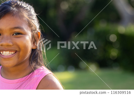 Outdoors, young biracial girl smiling brightly, wearing a pink top, copy space Outdoors, young biracial girl smiling brightly, wearing a pink top, copy space 116309516