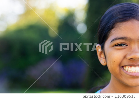 Outdoors, young biracial girl smiling brightly, showing her teeth, copy space 116309535