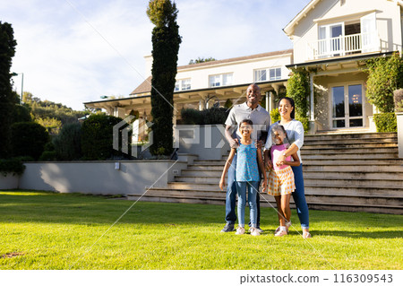 Outdoors, diverse family of four stands together smiling warmly by their home, copy space Outdoors, diverse family of four stands together smiling warmly by their home, copy space 116309543