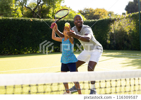 Outdoors, diverse father and daughter playing tennis on sunny day Outdoors, diverse father and daughter playing tennis on sunny day 116309587