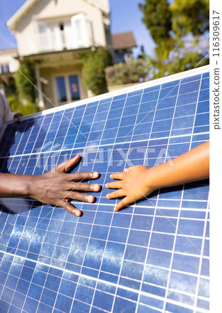 Outdoors, diverse father and daughter touching solar panel together 116309617