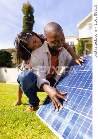 Outdoors, diverse father and daughter examining solar panel together Outdoors, diverse father and daughter examining solar panel together 116309619