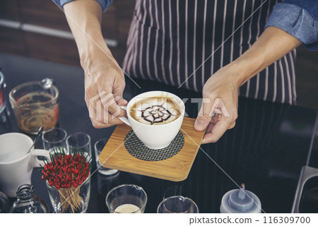 Coffee barista pour espresso shot and make latte art hot coffee cup. Cappuccino with milk in italian coffee shop cafe. Close up hands of barista make brown latte art for customer cafeteria. 116309700