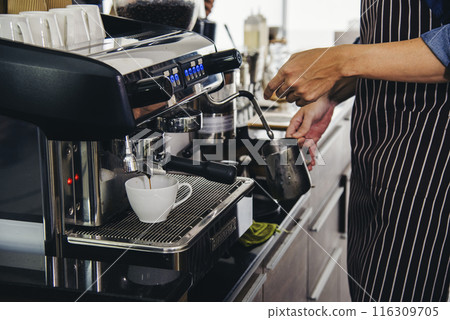 Close up hands coffee barista man make hot cup espresso shot from coffee machine. Cappuccino with milk in italian coffee shop cafe. Close up hands of barista use machine make black drinking hot cup 116309705