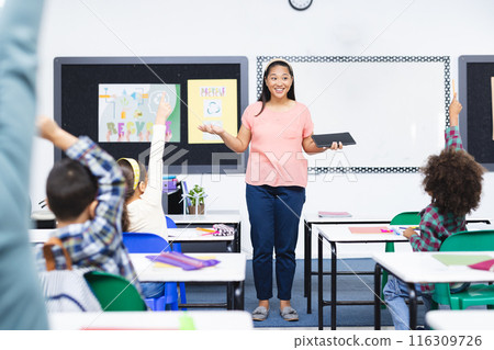 Biracial female teacher engaging with students in classroom 116309726