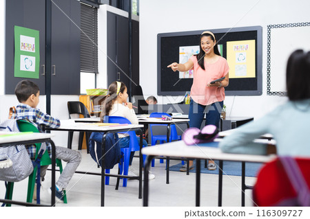 Biracial female teacher engaging with diverse students in classroom setting 116309727