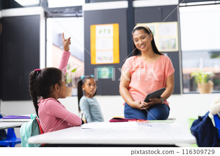 Biracial teacher interacting with students in classroom Biracial teacher interacting with students in classroom 116309729