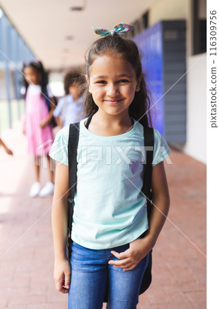 Biracial girl smiling with backpack, standing in front of school lockers Biracial girl smiling with backpack, standing in front of school lockers 116309756