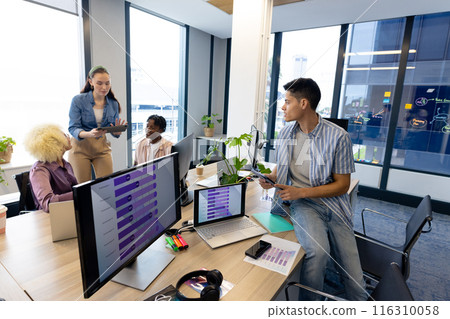 Diverse colleagues collaborate in modern office business; one shows a tablet, copy space Diverse colleagues collaborate in modern office business; one shows a tablet, copy space 116310058