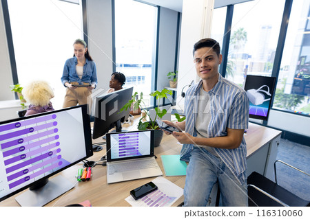 biracial man in modern office using smartphone, collaborating with colleagues biracial man in modern office using smartphone, collaborating with colleagues 116310060