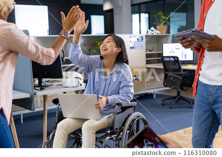 Business colleagues bond as an Asian woman in a wheelchair high-fives to boost teamwork Business colleagues bond as an Asian woman in a wheelchair high-fives to boost teamwork 116310080