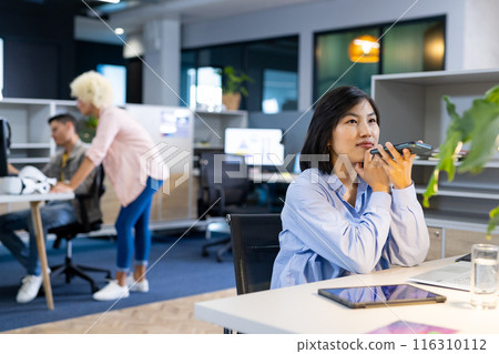 Asian woman using smartphone in modern office setting, business, copy space Asian woman using smartphone in modern office setting, business, copy space 116310112