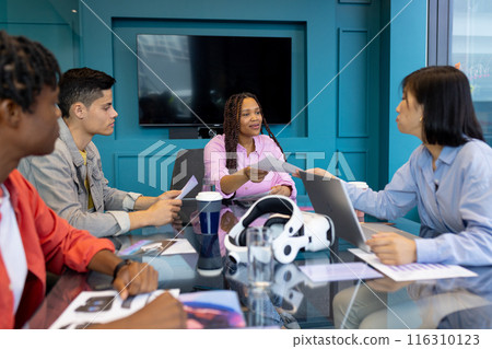 Diverse Business colleagues in meeting with a woman handing a document to another business Diverse Business colleagues in meeting with a woman handing a document to another business 116310123
