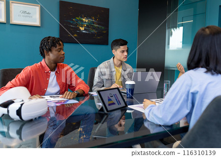 Young team collaborates on laptop and tablet in diverse business startup 116310139