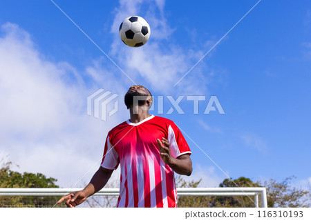 African American soccer player in a red and white jersey balancing soccer ball on head African American soccer player in a red and white jersey balancing soccer ball on head 116310193