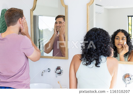Diverse couple getting ready in front of bathroom mirrors Diverse couple getting ready in front of bathroom mirrors 116310207