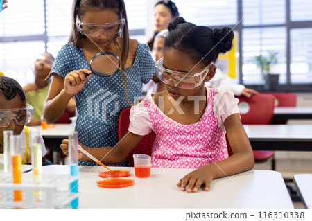 Diverse female teacher and schoolgirls with chemistry items and liquids in elementary school class Diverse female teacher and schoolgirls with chemistry items and liquids in elementary school class 116310338