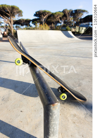 Skateboard balancing on rail at skatepark, ready for tricks and stunts, copy space 116310664