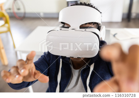 Using VR headset, African American male student exploring virtual reality in classroom 116310728