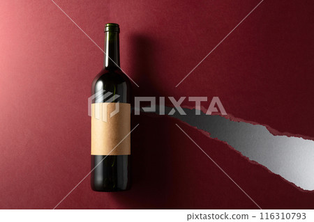 Bottle of red wine with old empty label on a dark red background. Bottle of red wine with old empty label on a dark red background. 116310793