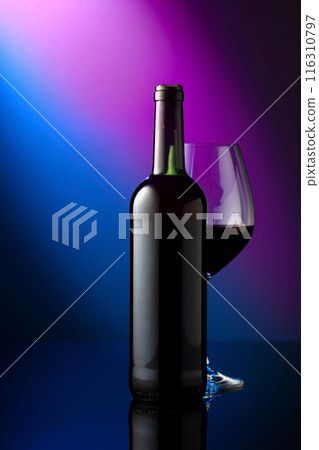 Glass and bottle of red wine on a blue background. 116310797