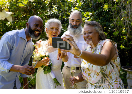 Group of friends taking selfie and celebrating with champagne outdoors 116310937