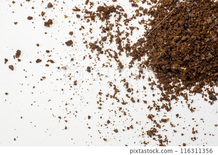 Heap of ground coffee beans creating a textured background on white surface 116311356