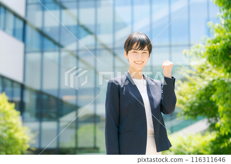 A woman in a suit standing in front of an office building A woman in a suit standing in front of an office building 116311646