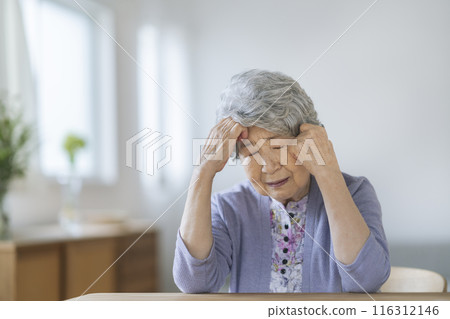 A woman in her 80s holding her head A woman in her 80s holding her head 116312146