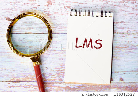 LMS - Learning Management System acronym. LMS in a notebook next to a magnifying glass on old boards 116312528