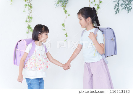 Elementary school students holding hands and carrying school bags 116313183