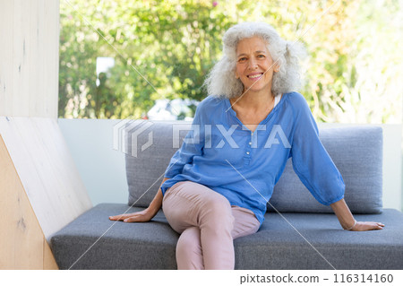 Outdoors, Smiling senior woman sitting on couch, enjoying relaxing moment at home Outdoors, Smiling senior woman sitting on couch, enjoying relaxing moment at home 116314160