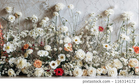 A wall of marble is covered in a beautiful arrangement of mostly white and peach flowers with hints of red. 116314172