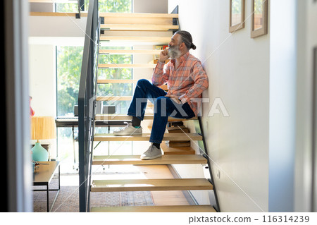 Sitting on stairs, senior man drinking coffee and looking out window at home 116314239