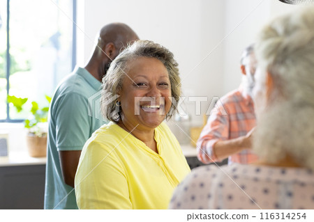 Smiling senior woman enjoying time with friends in cozy home gathering Smiling senior woman enjoying time with friends in cozy home gathering 116314254