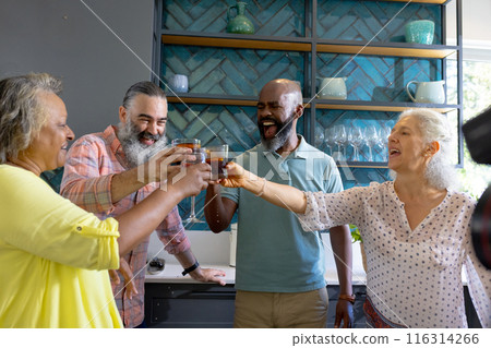 At home, Group of friends toasting with drinks in kitchen, enjoying time together 116314266