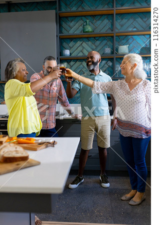 At home, Group of friends toasting drinks in modern kitchen, enjoying time together 116314270