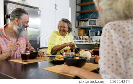 Enjoying meal together, group of senior friends laughing and dining at home Enjoying meal together, group of senior friends laughing and dining at home 116314274