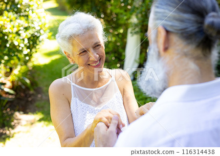 Smiling bride holding hands with groom, at outdoor wedding 116314438