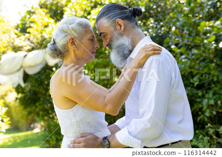 Embracing outdoors, senior bride and groom at wedding in garden 116314442