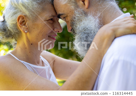 Embracing and smiling, senior bride and groom at wedding outdoors in park 116314445